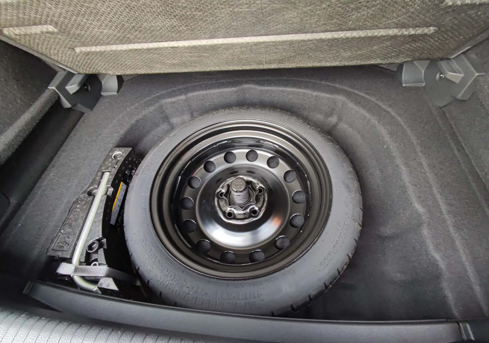 Vue plongeante sur la roue de secours noire dans le coffre d’une Volkswagen Golf blanche 1.5 TSI EVO 2019.