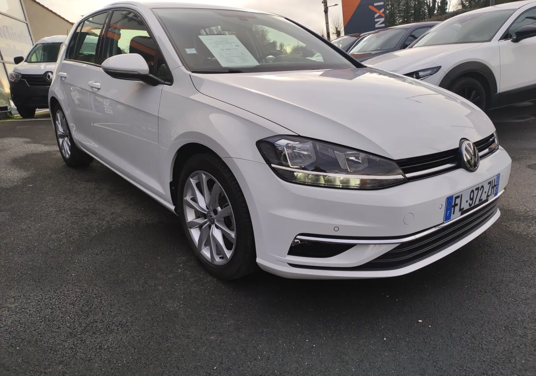 Volkswagen Golf 1.5 TSI blanc vue 3/4 avant droit, avec phares LED et jantes alliage visibles.