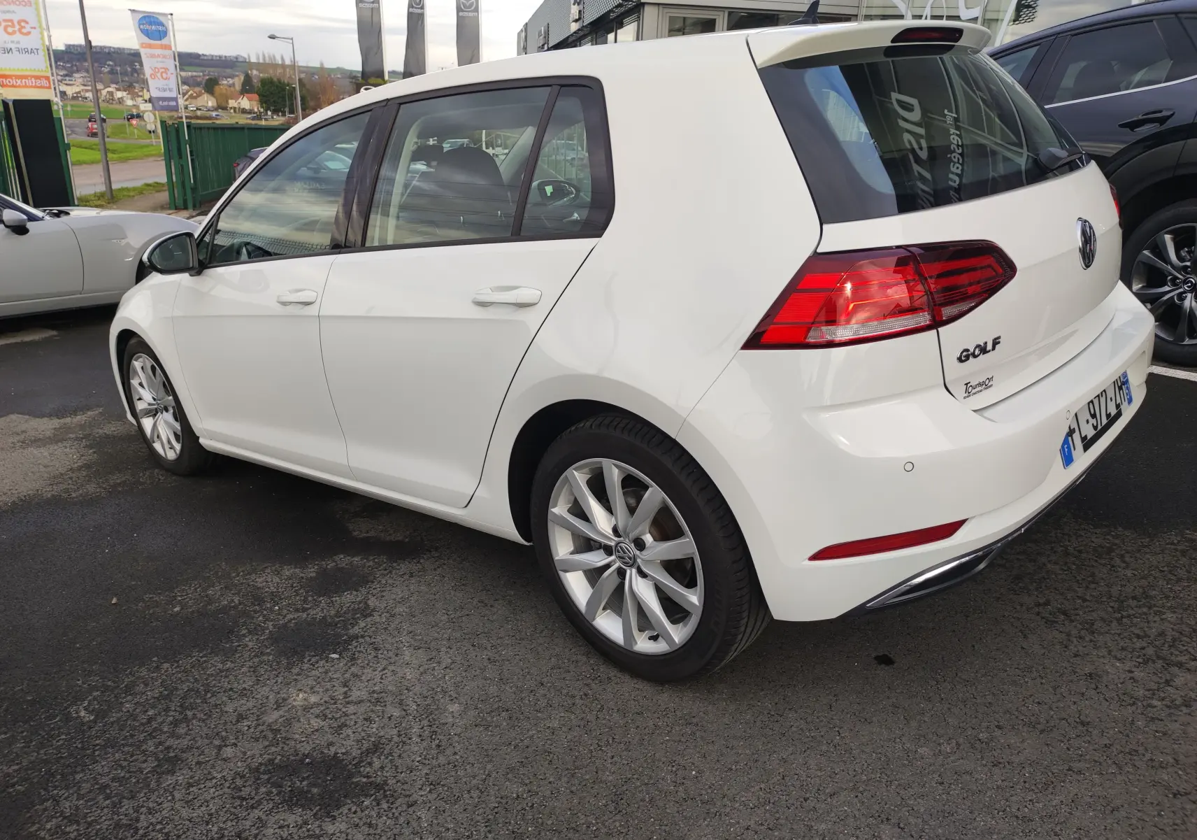 Vue 3/4 arrière droite d'une Volkswagen Golf blanche 1.5 TSI EVO 2019 avec jantes alliage et feux arrière LED.