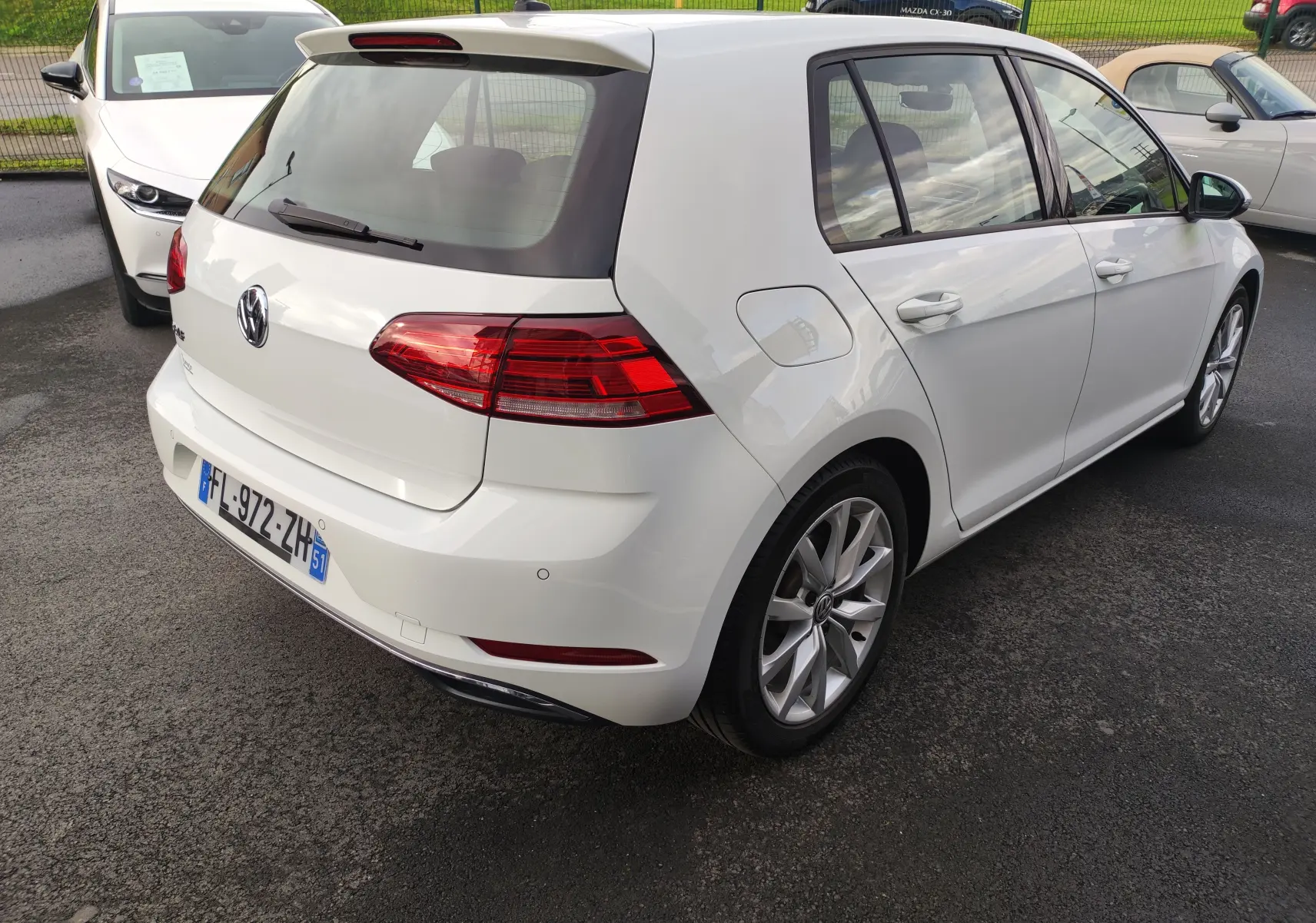 Vue 3/4 arrière droite d'une Volkswagen Golf blanche 1.5 TSI EVO 2019 avec jantes alliage et feux arrière LED.