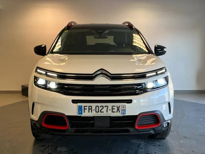 Vue frontale d'un Citroën C5 Aircross blanc nacré avec feux allumés et détails rouges sur le pare-chocs.