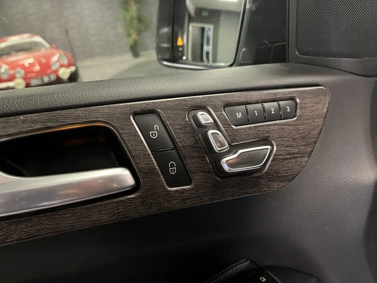 Détail des commandes de réglage de siège sur la porte côté gauche d'une Mercedes GLE 400 gris, finition cuir.