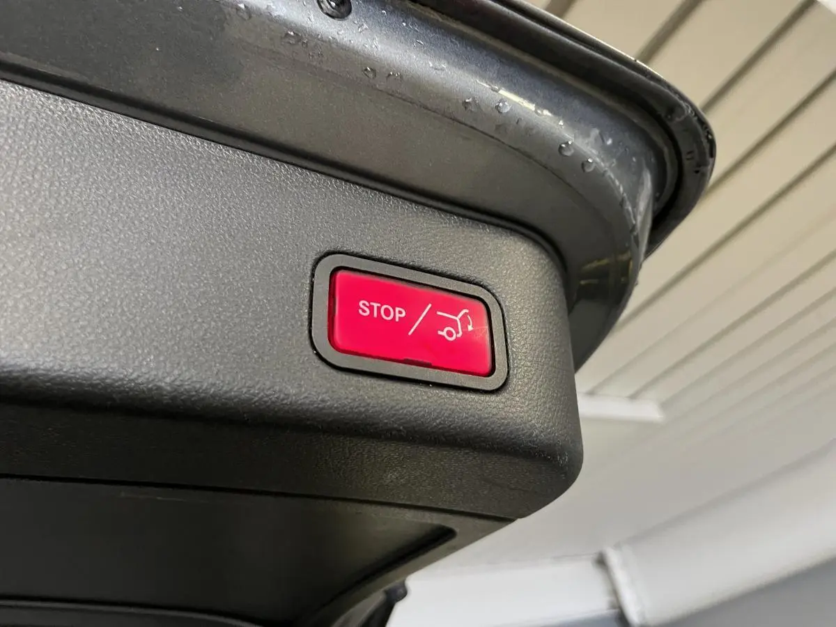 Bouton rouge stop pour fermeture électrique du hayon sur un Mercedes GLE gris, vue en gros plan du coffre ouvert.