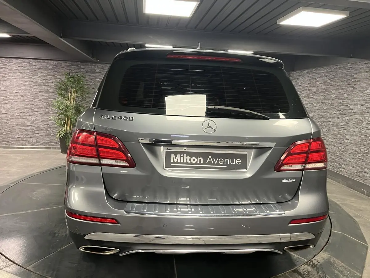 Vue arrière d'un Mercedes GLE 400 gris métallisé avec feux rouges et double sortie d'échappement chromée.