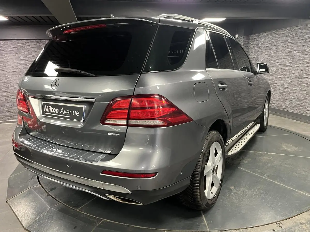 Vue 3/4 arrière droite d'un Mercedes GLE 400 gris métallisé avec jantes alliage et vitres teintées foncées.