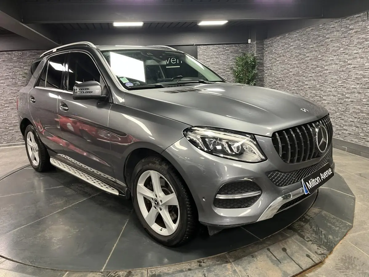 Vue 3/4 avant droite d'un Mercedes GLE 400 gris métallisé avec jantes alliage et barres de toit chromées.