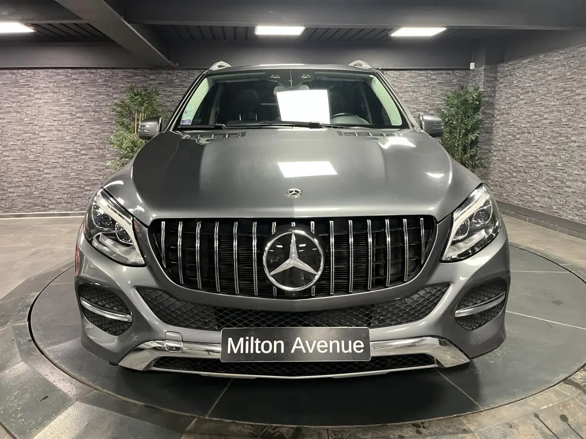 Vue frontale d'un Mercedes GLE 400 gris métallisé avec calandre noire à barrettes verticales et logo central.