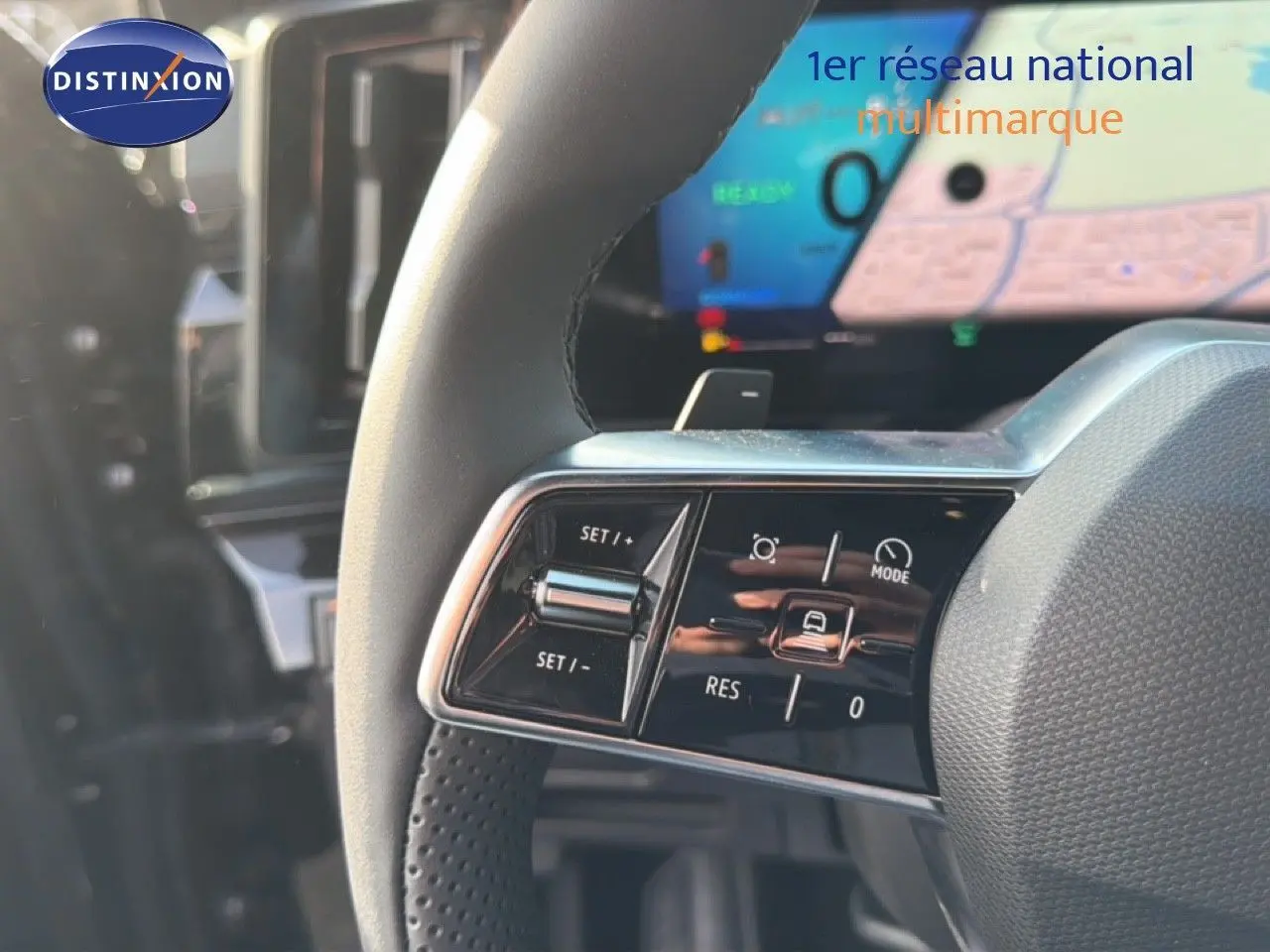 Gros plan sur les commandes du volant d'un Renault Espace noir étoile métal, avec écran numérique en arrière-plan.