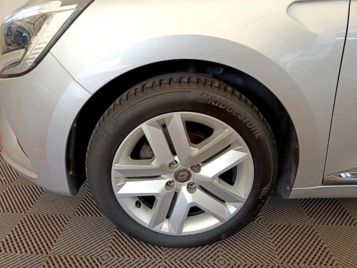 Gros plan sur la roue avant gauche gris clair d'une Renault Clio Business TCe 100 avec jante alliage à cinq branches.