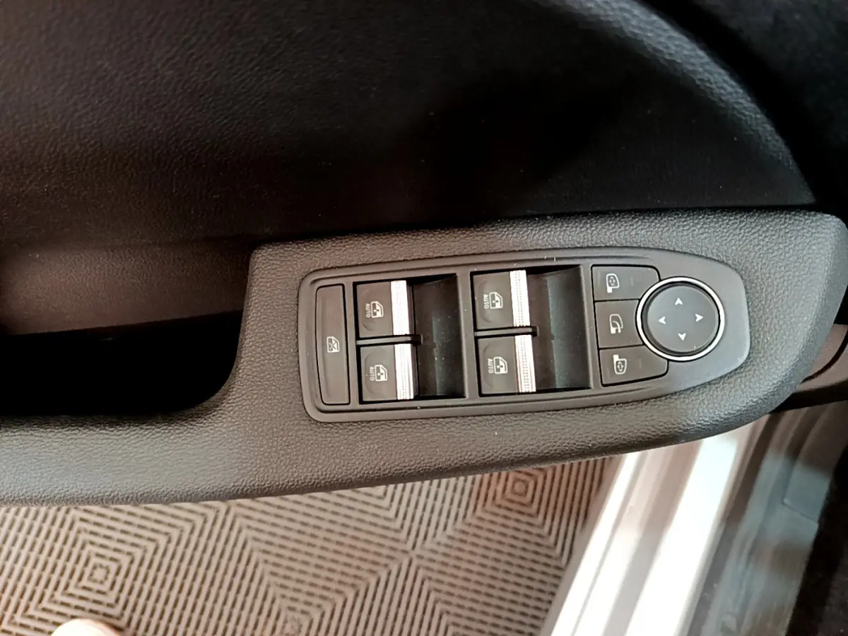 Panneau de commandes des vitres et rétroviseurs côté conducteur de la Renault Clio Business gris clair, vue intérieure rapprochée.