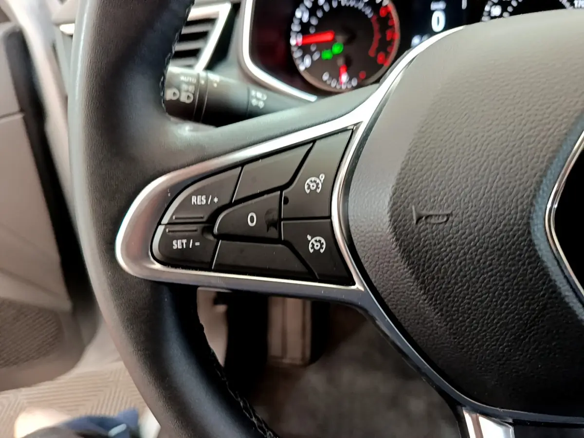 Gros plan sur les commandes du régulateur de vitesse au volant en cuir noir de la Renault Clio Business TCe 100 2020.