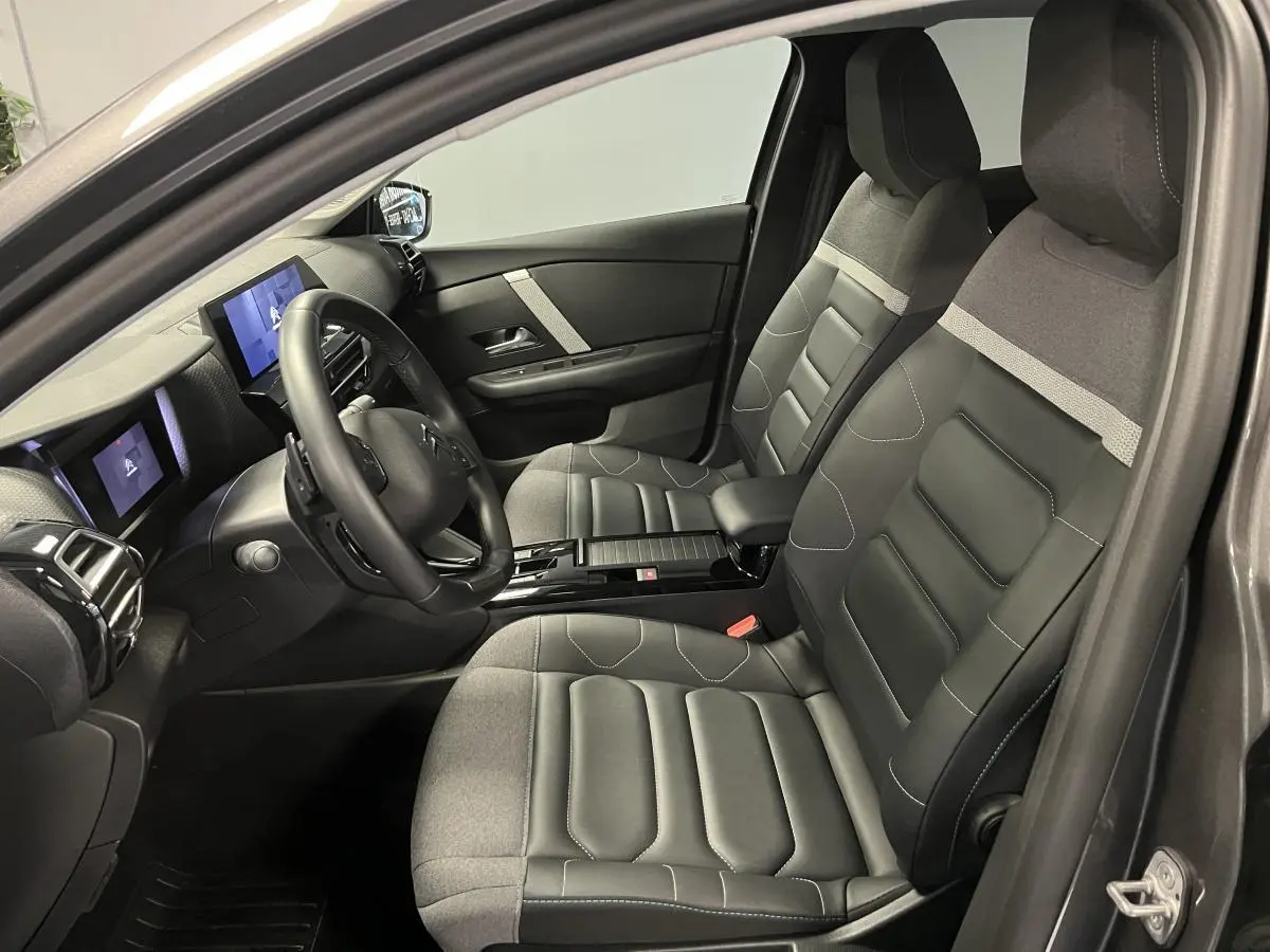 Intérieur avant de la Citroën C4 X gris 2024, sièges Advanced Comfort bicolores et tableau de bord avec écran tactile.
