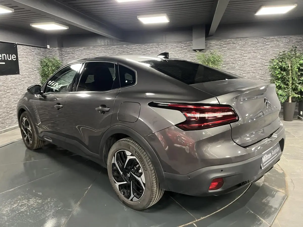 Vue 3/4 arrière droite d'une Citroën C4 X gris métallisé avec feux arrière LED et jantes alliage 18 pouces.