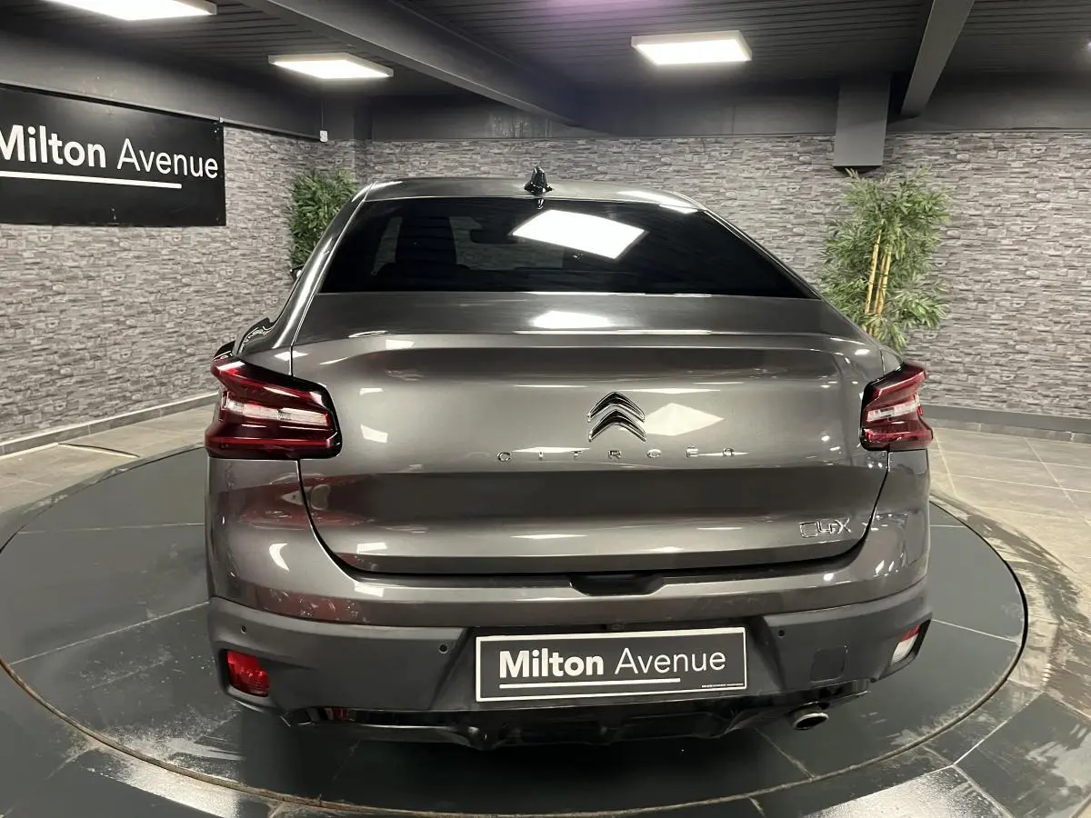 Vue arrière d'une Citroën C4 X gris métallisé 2024 avec feux LED et logo centré dans un showroom.