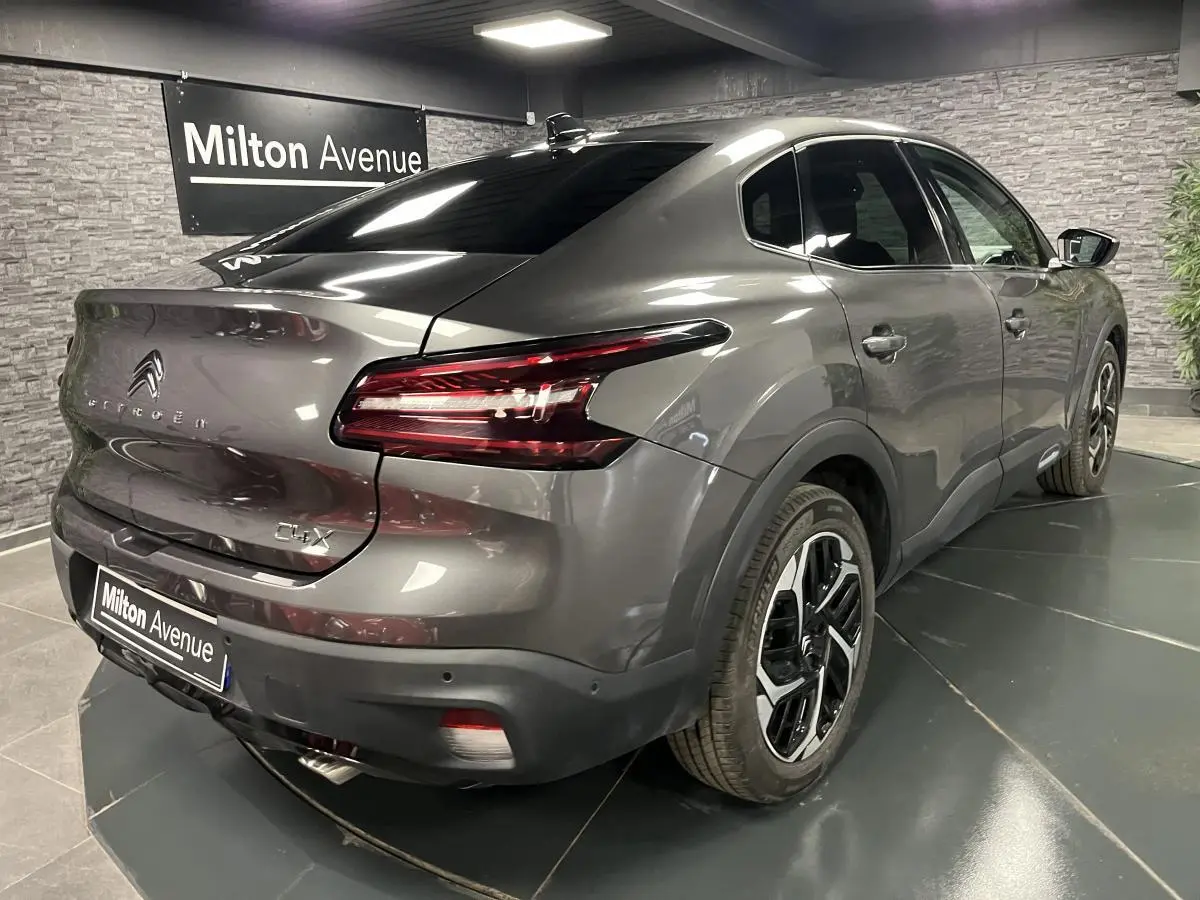 Vue 3/4 arrière droite d'une Citroën C4 X gris métallisé avec jantes alliage 18'' et feux LED en V.