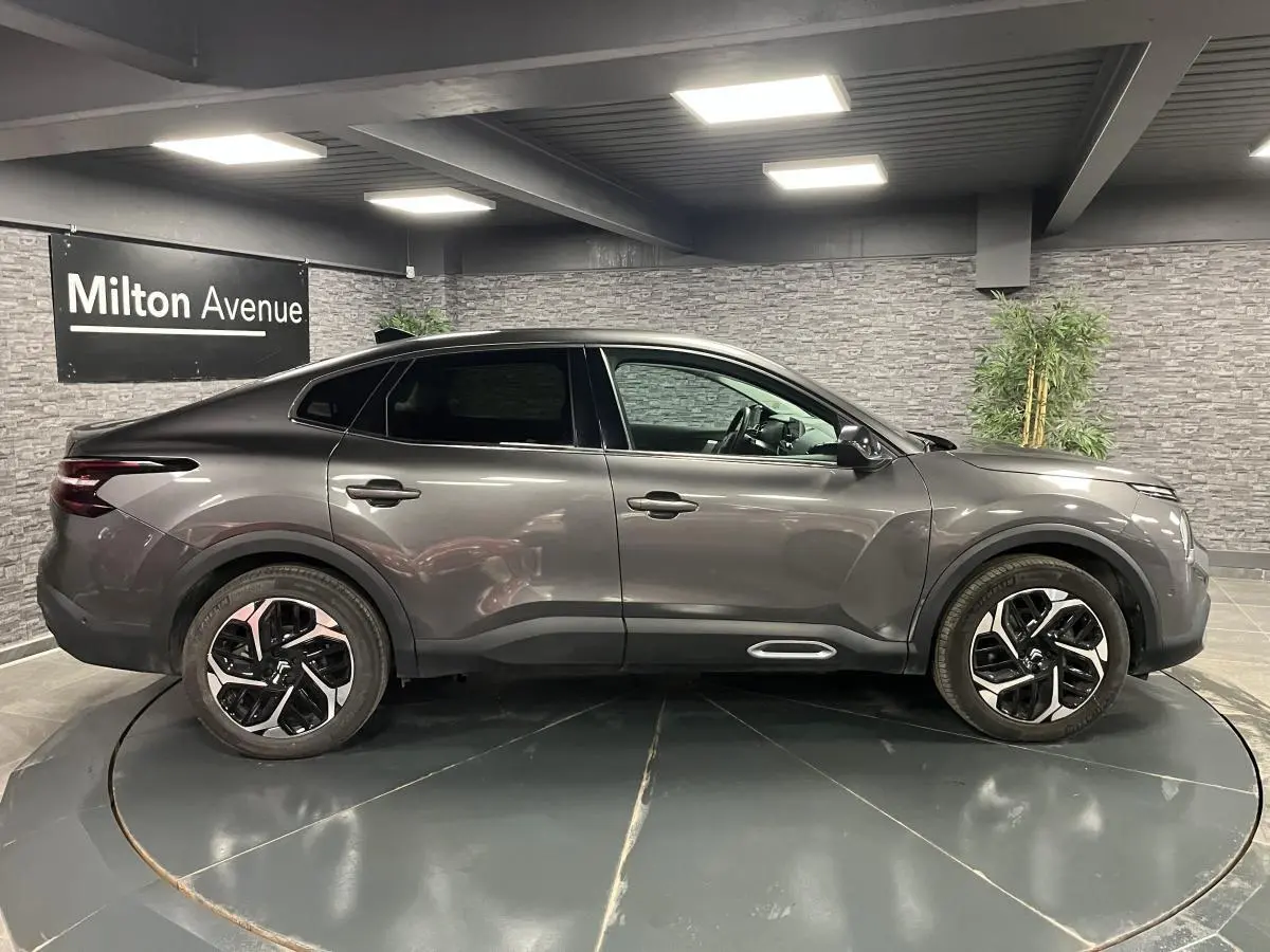 Profil côté gauche du Citroën C4 X gris métallisé 2024 avec jantes alliage 18'' et lignes fluides élégantes.