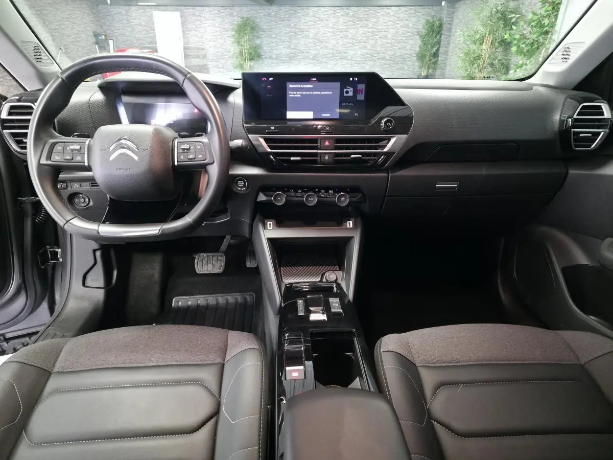Intérieur noir du Citroën C4 X 2024, vue frontale du tableau de bord avec écran tactile et volant multifonction.