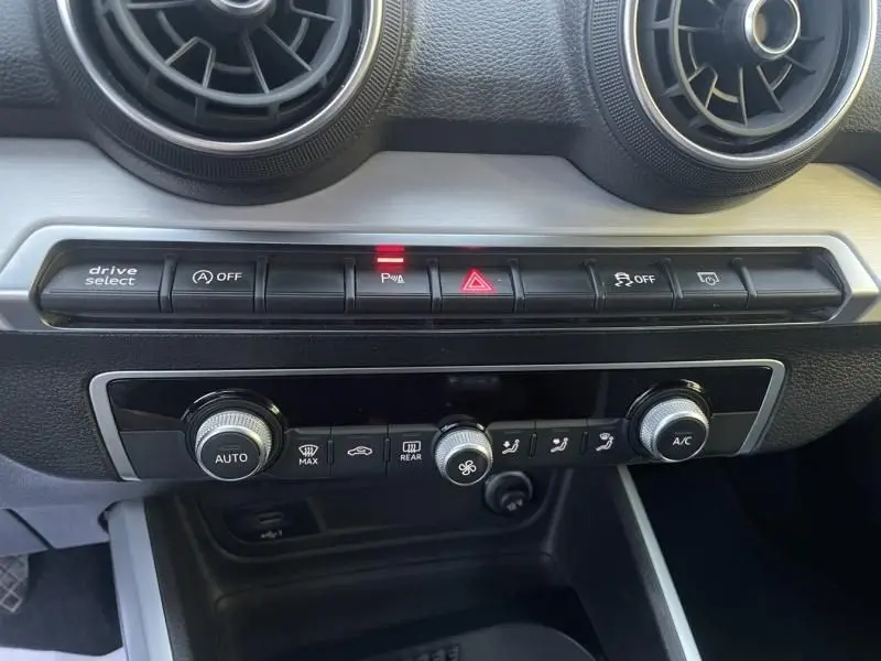 Vue rapprochée de la console centrale de l'Audi Q2 blanche 30 TFSI 116 SPORT LIMITED 2020, montrant les commandes de climatisation et boutons de fonction.