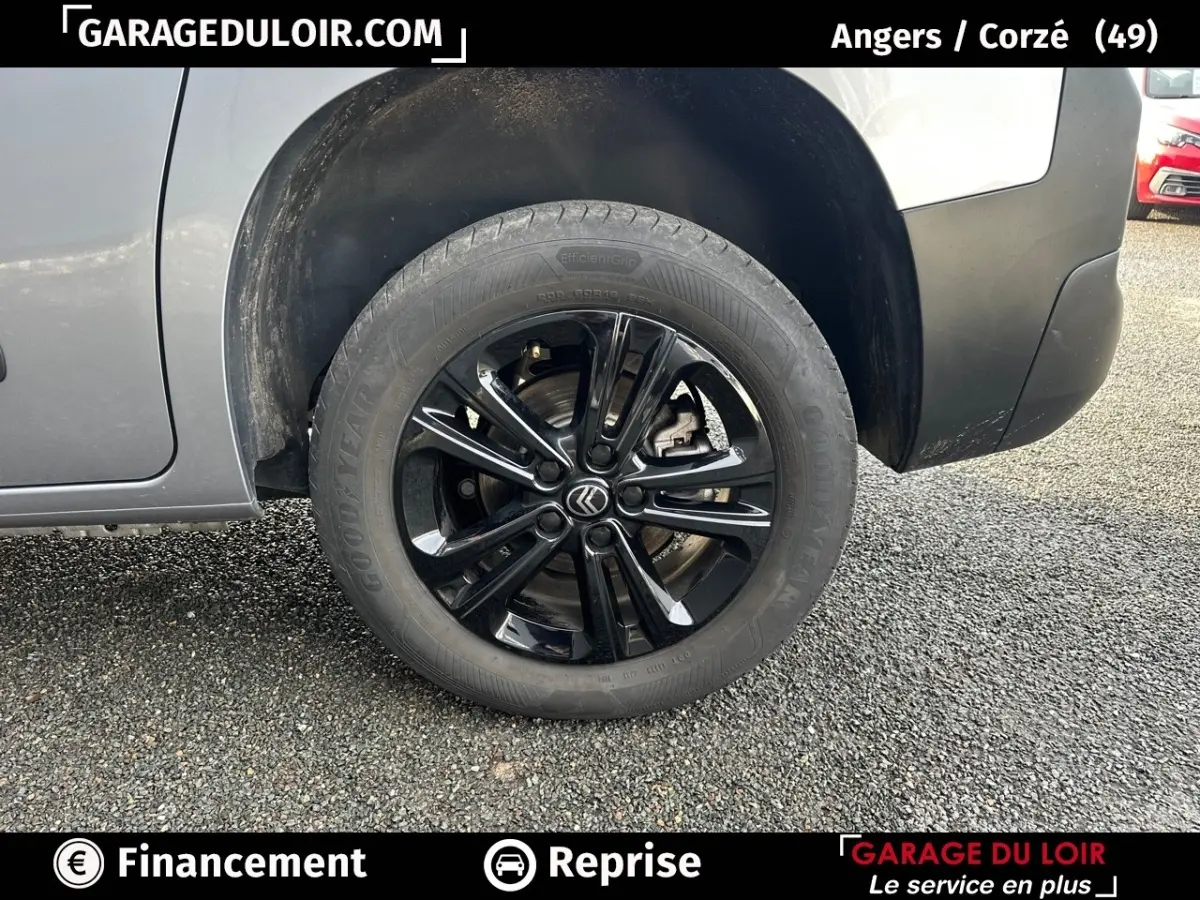 Gros plan sur la roue avant gauche noire brillante d’un Citroën Berlingo gris clair 2024, avec jante en alliage.