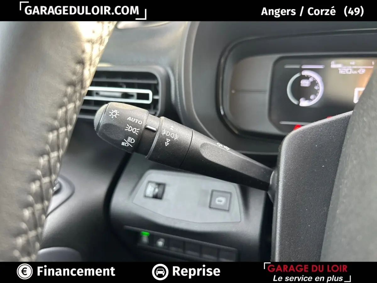 Gros plan sur la manette des feux et clignotants à gauche du volant cuir dans un Citroën Berlingo gris clair 2024.