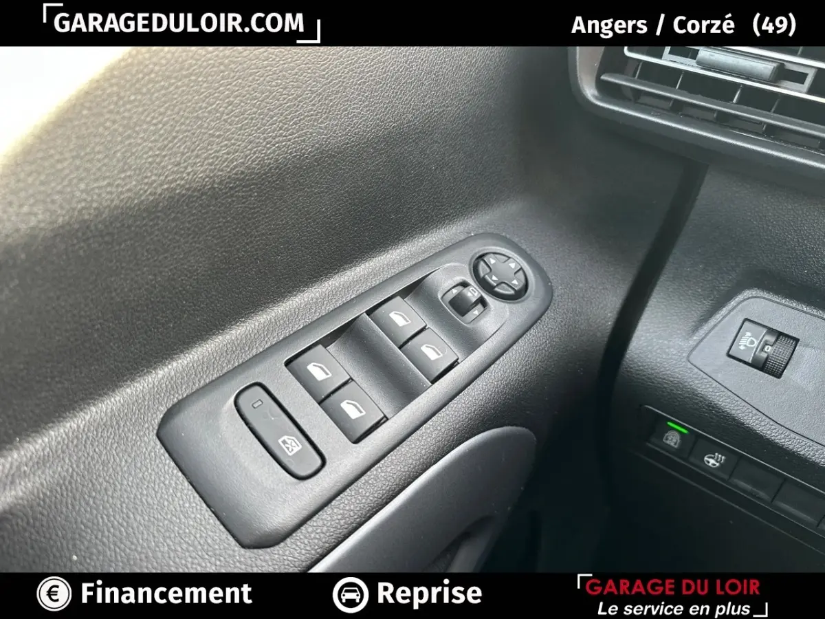 Gros plan sur les commandes des vitres électriques et réglages des rétroviseurs côté conducteur du Citroën Berlingo gris clair 2024.