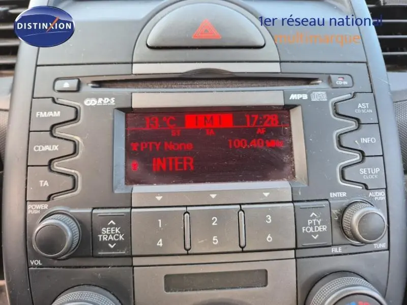 Vue rapprochée du tableau de bord de la KIA SOUL 2010 montrant l’autoradio avec écran rouge affichant la station FM.