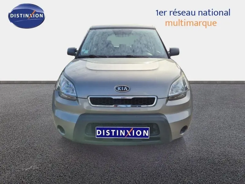Vue frontale d'une KIA SOUL 1.6 16v Plug 2010 en peinture métal gris clair, avec calandre noire et logo Kia visible.