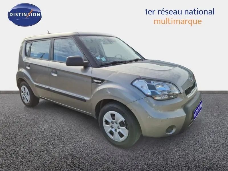 Vue 3/4 avant d'une KIA SOUL 1.6 16v Plug 2010 gris métallisé avec phares et jantes visibles sur fond neutre.