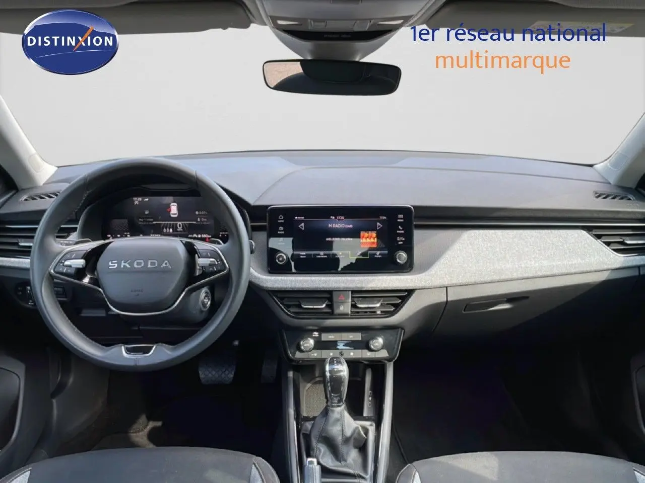 Vue intérieure avant du Skoda Kamiq gris argent, mettant en valeur le tableau de bord moderne et l’écran tactile central.