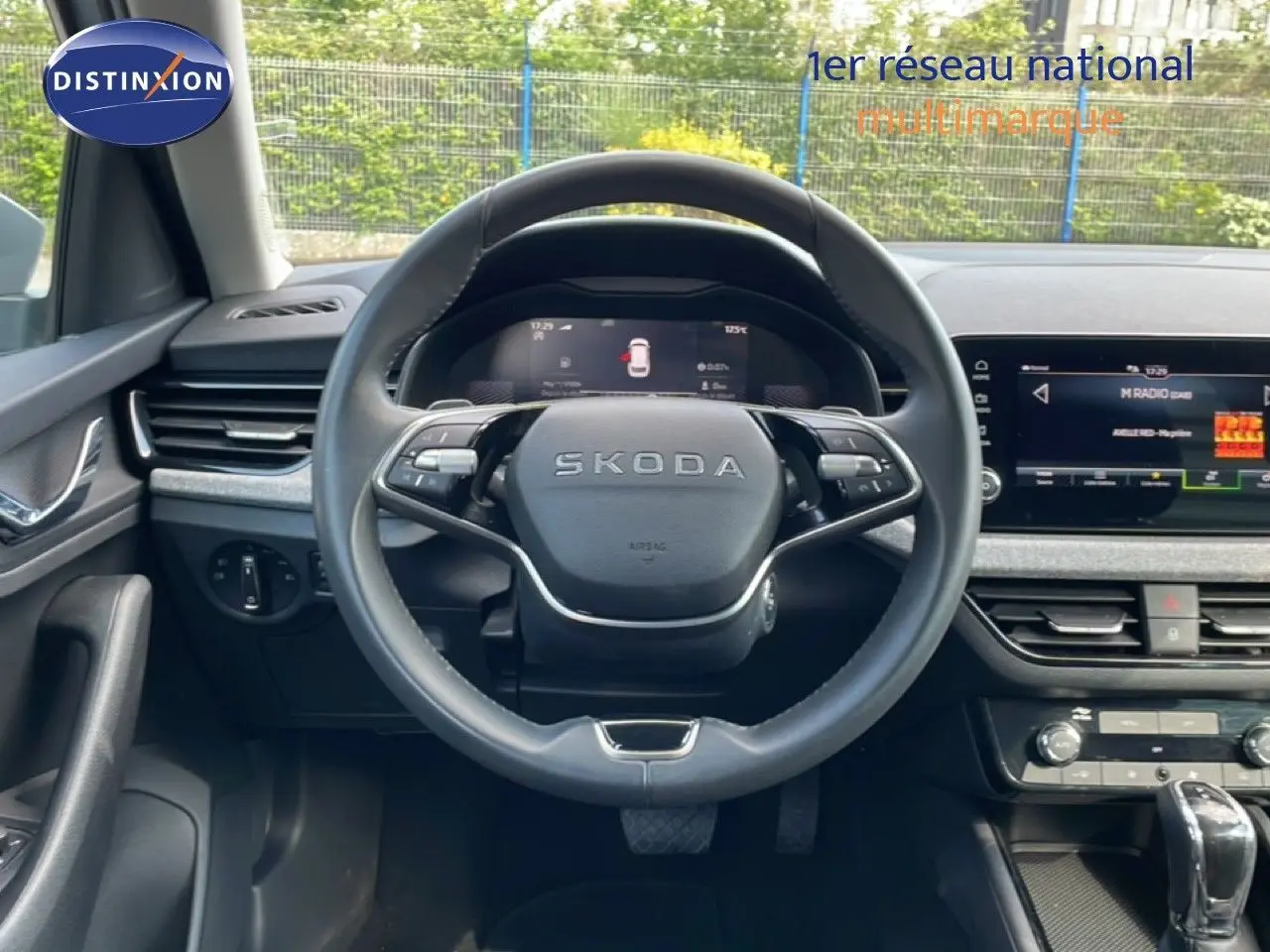 Vue intérieure centrée sur le volant cuir SKODA d'un KAMIQ gris argent 2025, avec tableau de bord digital et écran tactile.