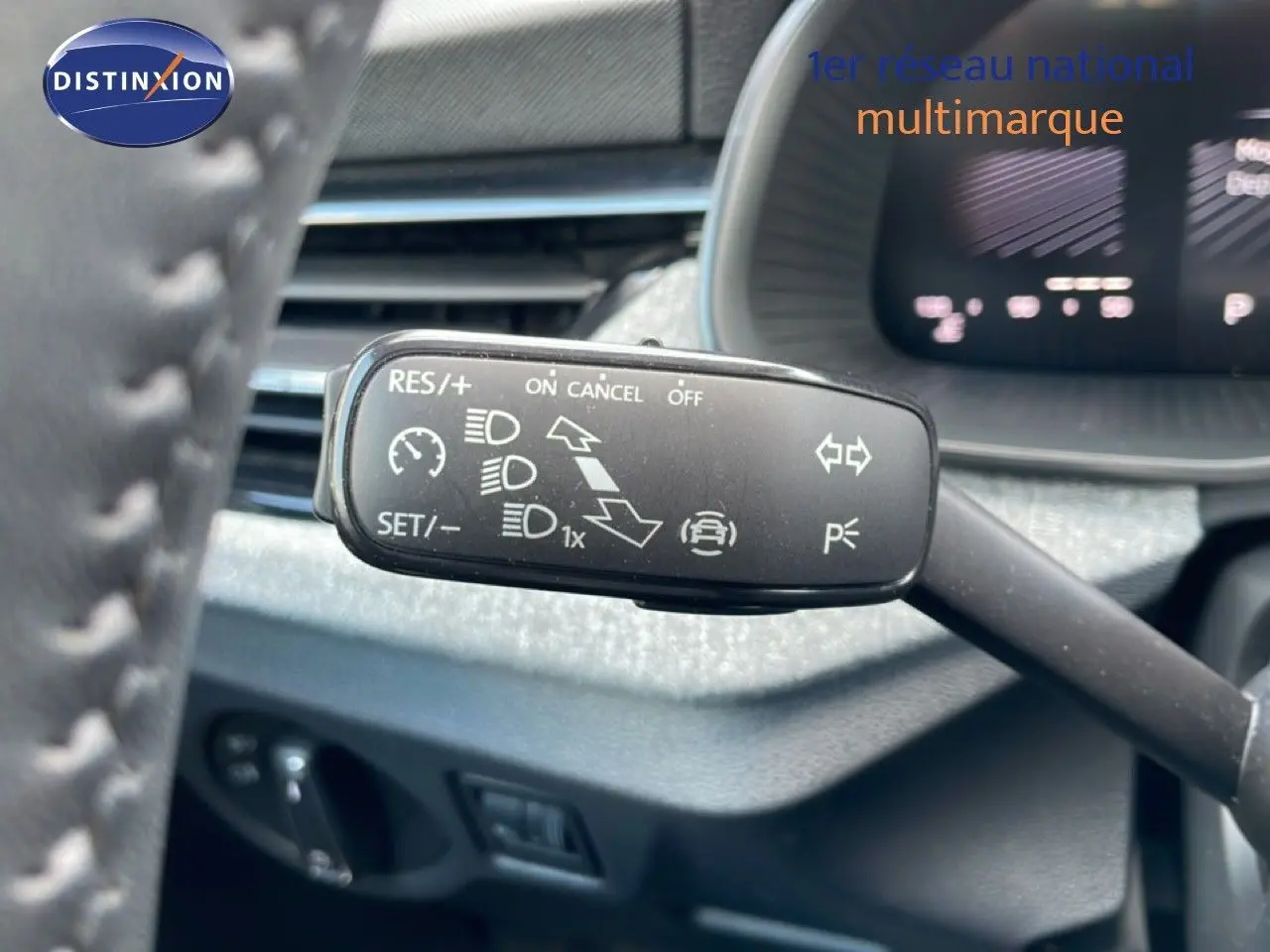 Gros plan sur la commande de régulateur de vitesse à gauche du volant dans l’habitacle du Skoda Kamiq gris argent.