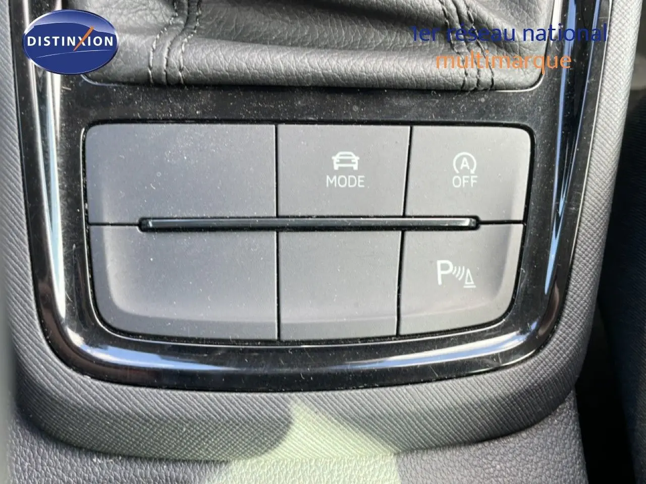 Gros plan sur les boutons de commande du mode de conduite et du stationnement assisté dans une Skoda Kamiq gris argent 2025.
