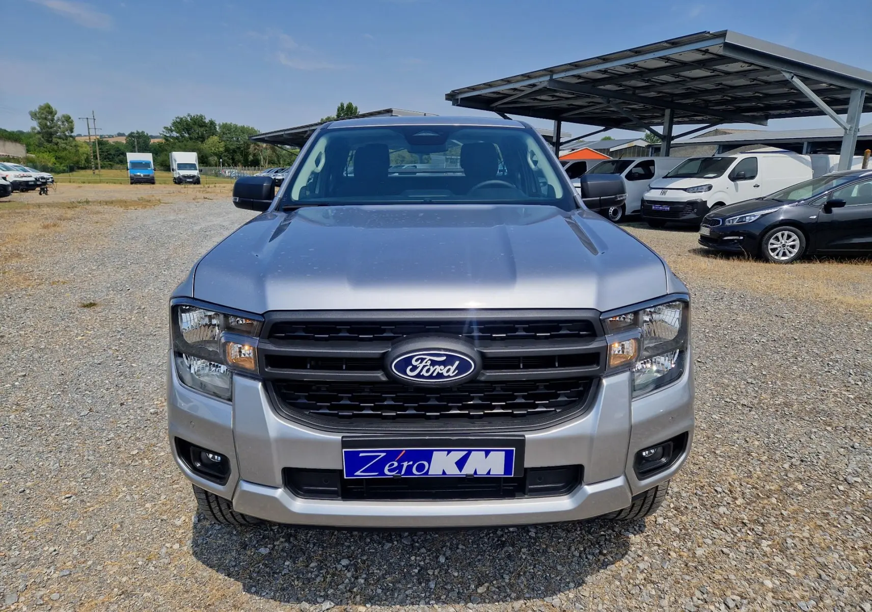Vue avant d’un Ford Ranger Super Cabine gris iconic avec calandre noire et plaque d’immatriculation Zero KM visible.