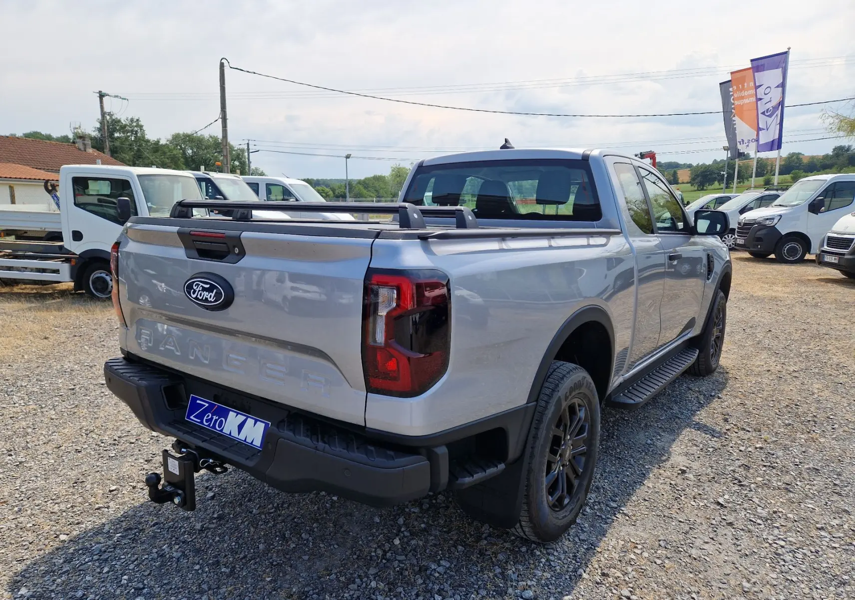 Vue 3/4 arrière droite du Ford Ranger Super Cabine gris Iconic avec barre de plateau et attelage visible.
