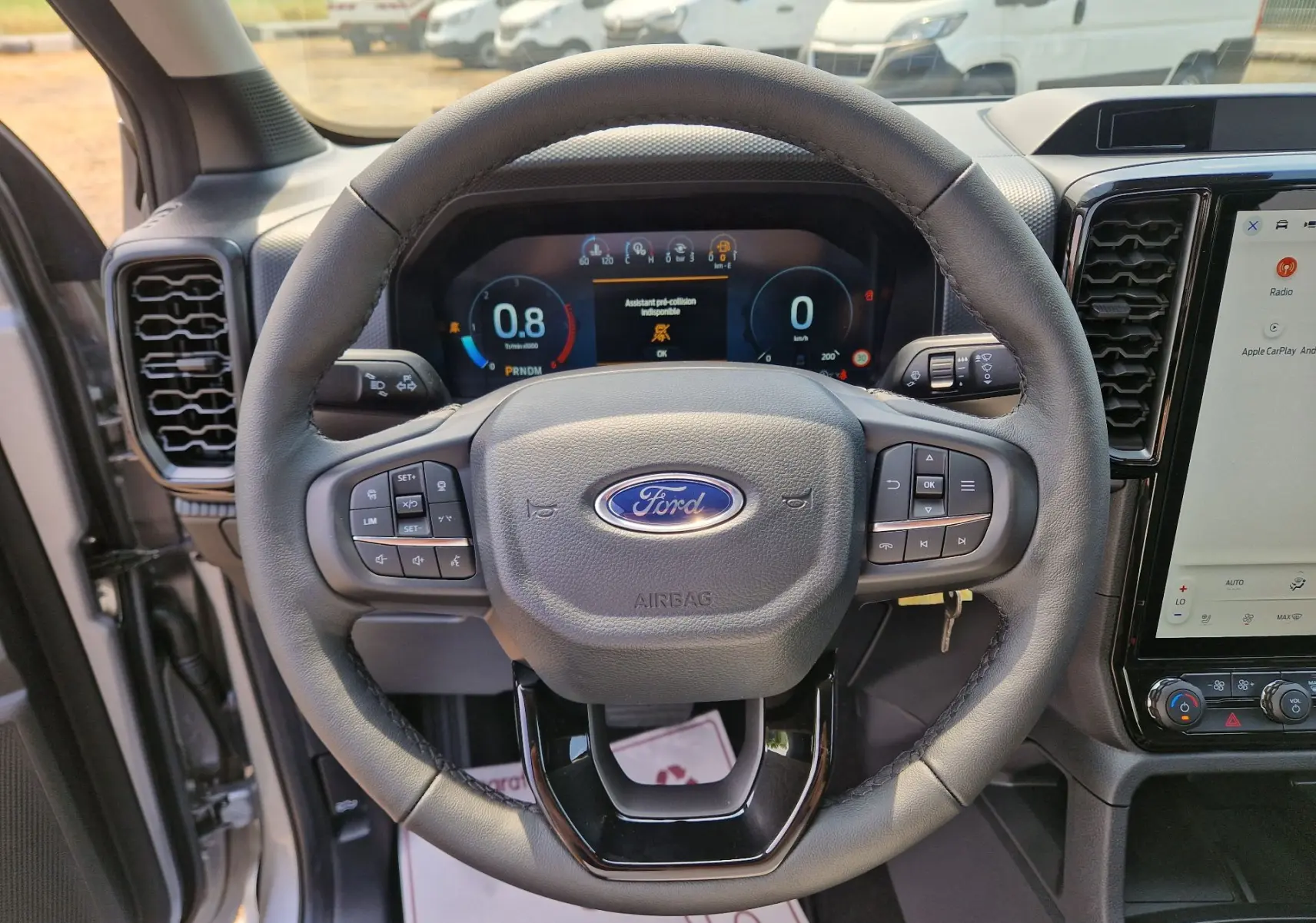 Vue intérieure centrée sur le volant du Ford Ranger Super Cabine gris, avec tableau de bord numérique et écran tactile visible.