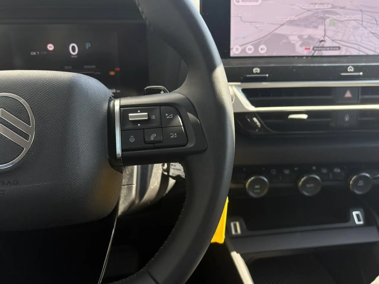 Gros plan sur le volant et tableau de bord du Citroën C4 Hybrid 2025, avec écran tactile de navigation visible.