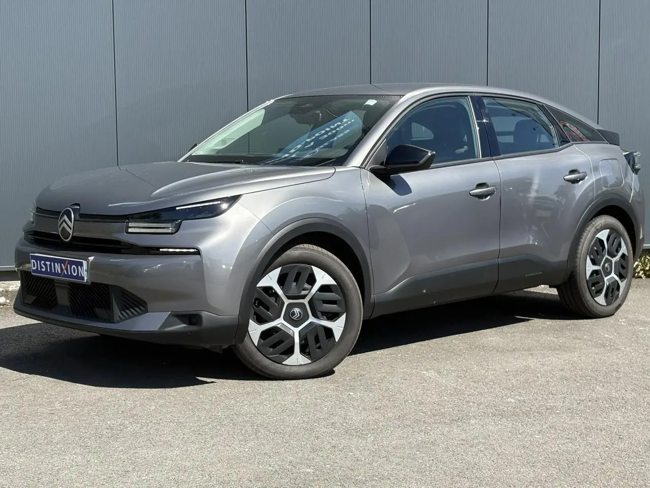Vue 3/4 avant droite d'une Citroën C4 Hybrid 145 gris Mercury avec jantes distinctives et calandre moderne.