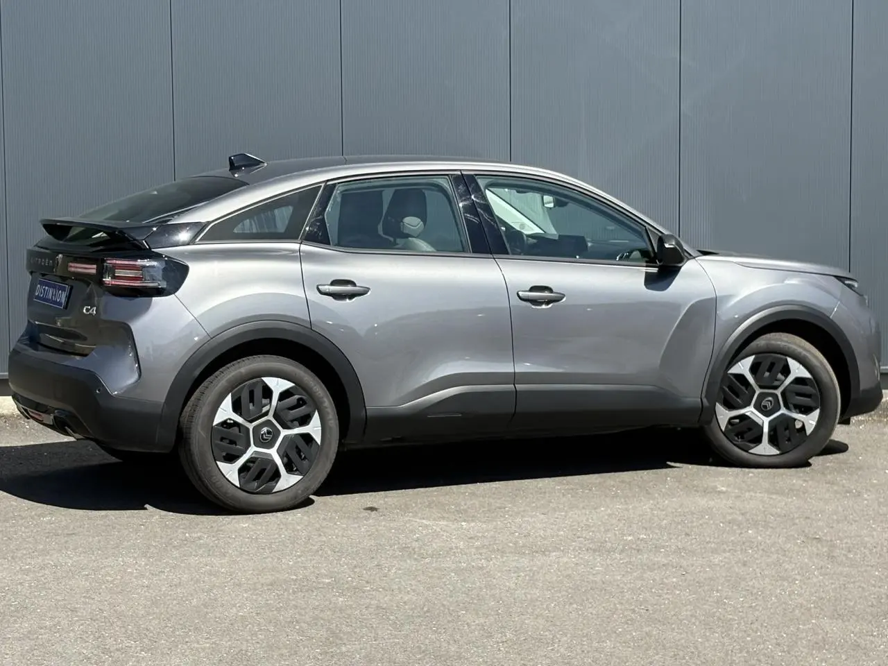 Vue latérale droite d'une Citroën C4 Hybrid 145 gris Mercury avec jantes distinctives et toit noir.