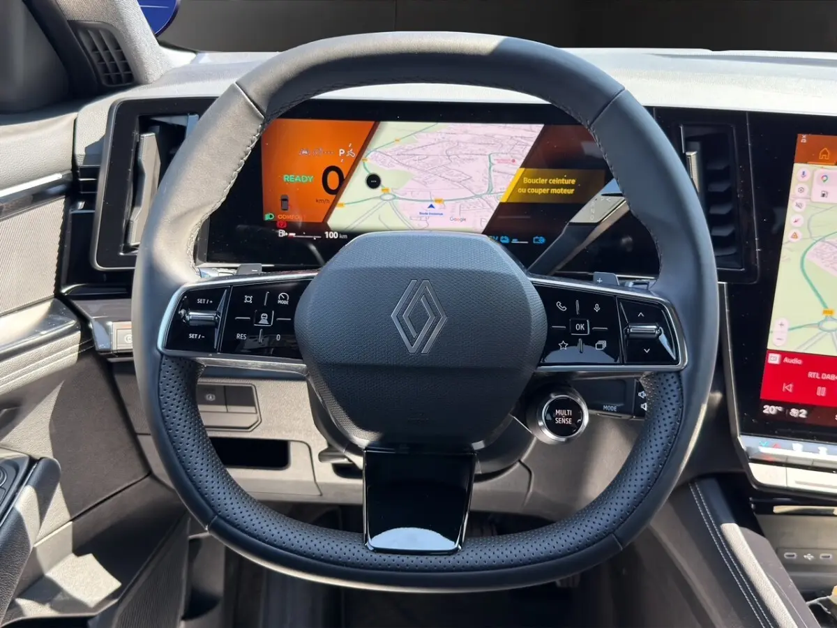 Vue centrée sur le volant noir perforé de la Renault Rafale 2025 avec tableau de bord numérique et écran tactile visible.