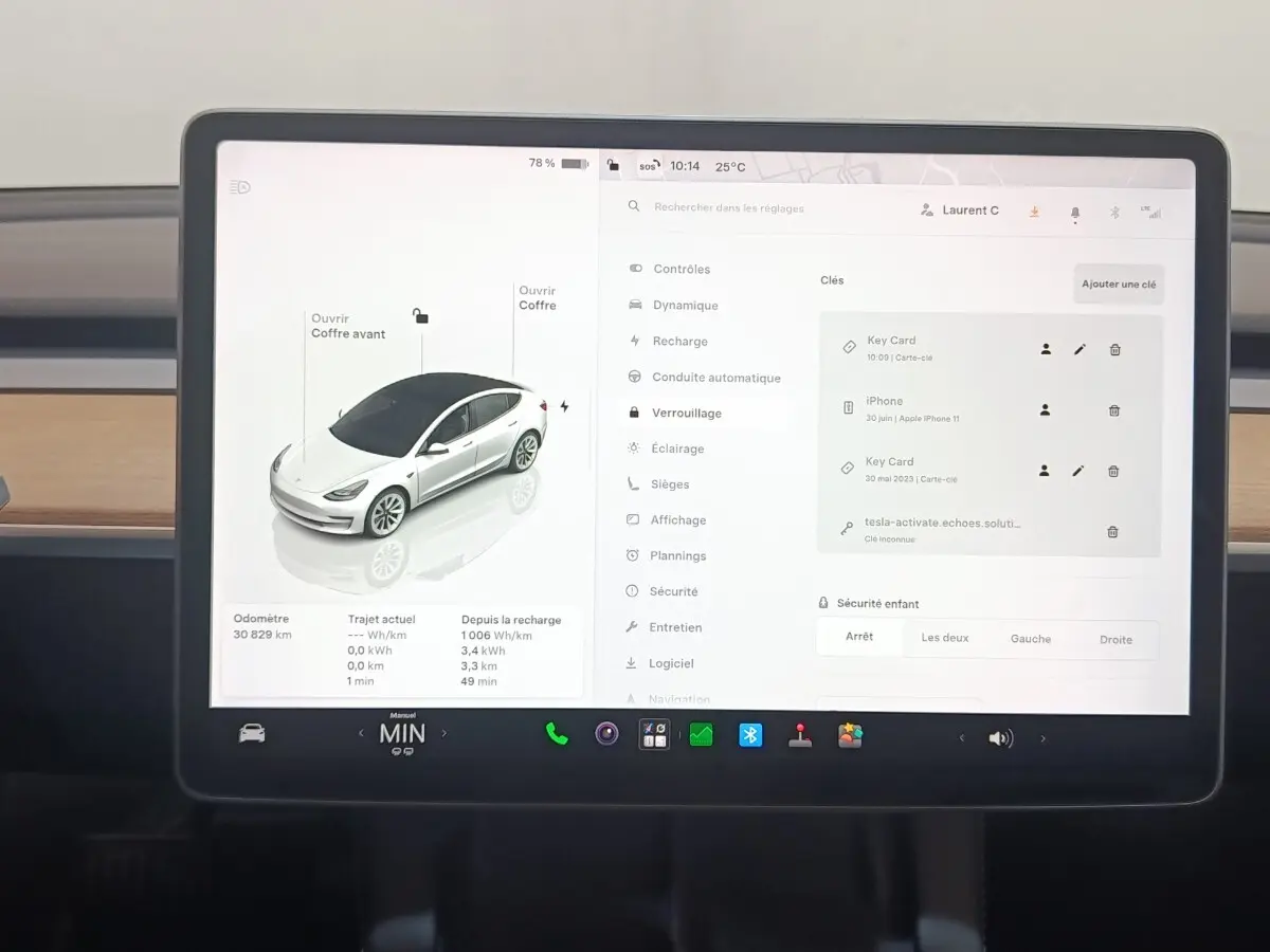 Écran tactile central affichant l'interface de contrôle d'une Tesla Model 3 blanche, vue intérieure frontale.