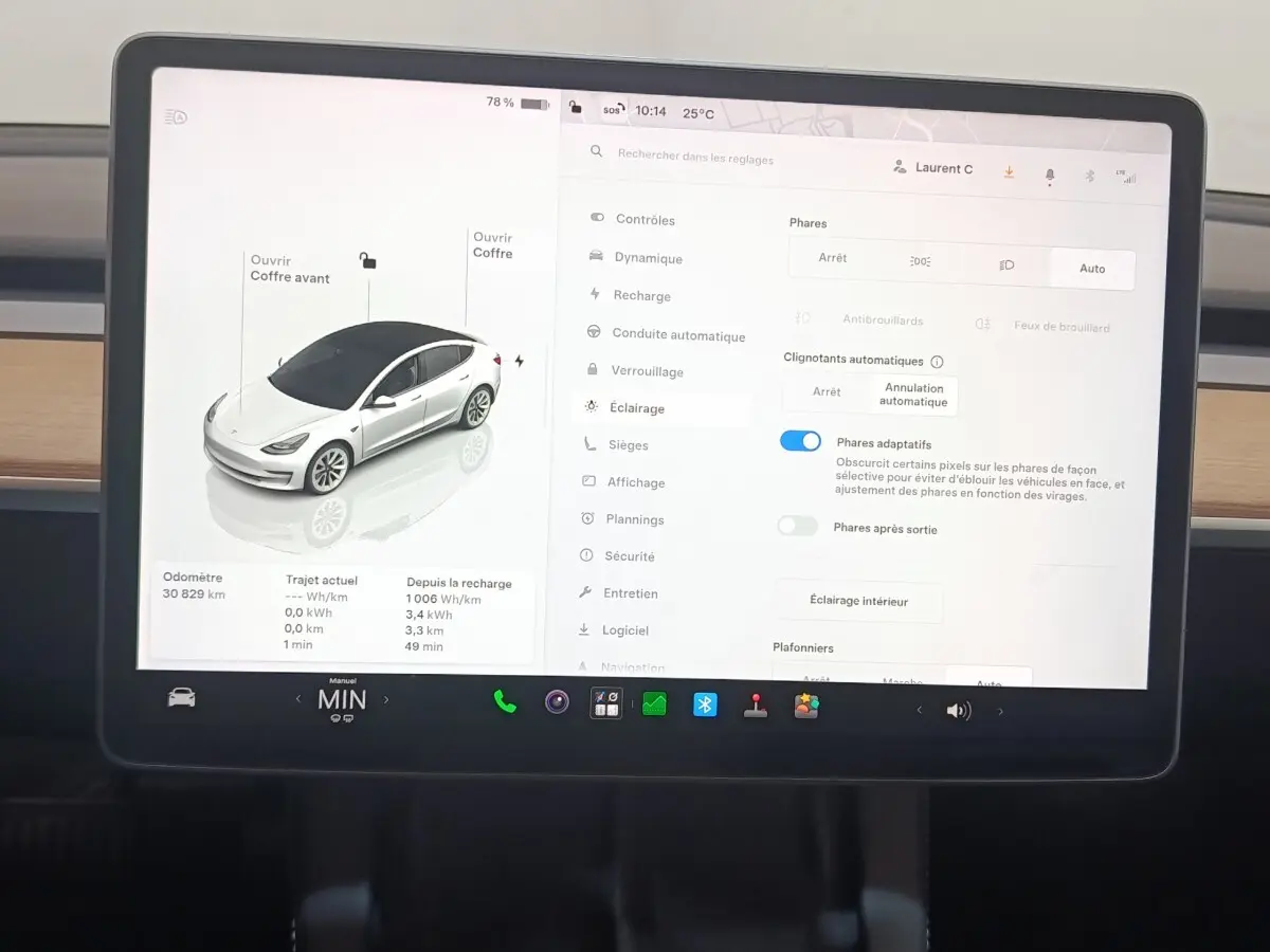 Écran tactile central de Tesla Model 3 blanc 2022 montrant les réglages d’éclairage et l’icône de la voiture en vue 3/4 avant.