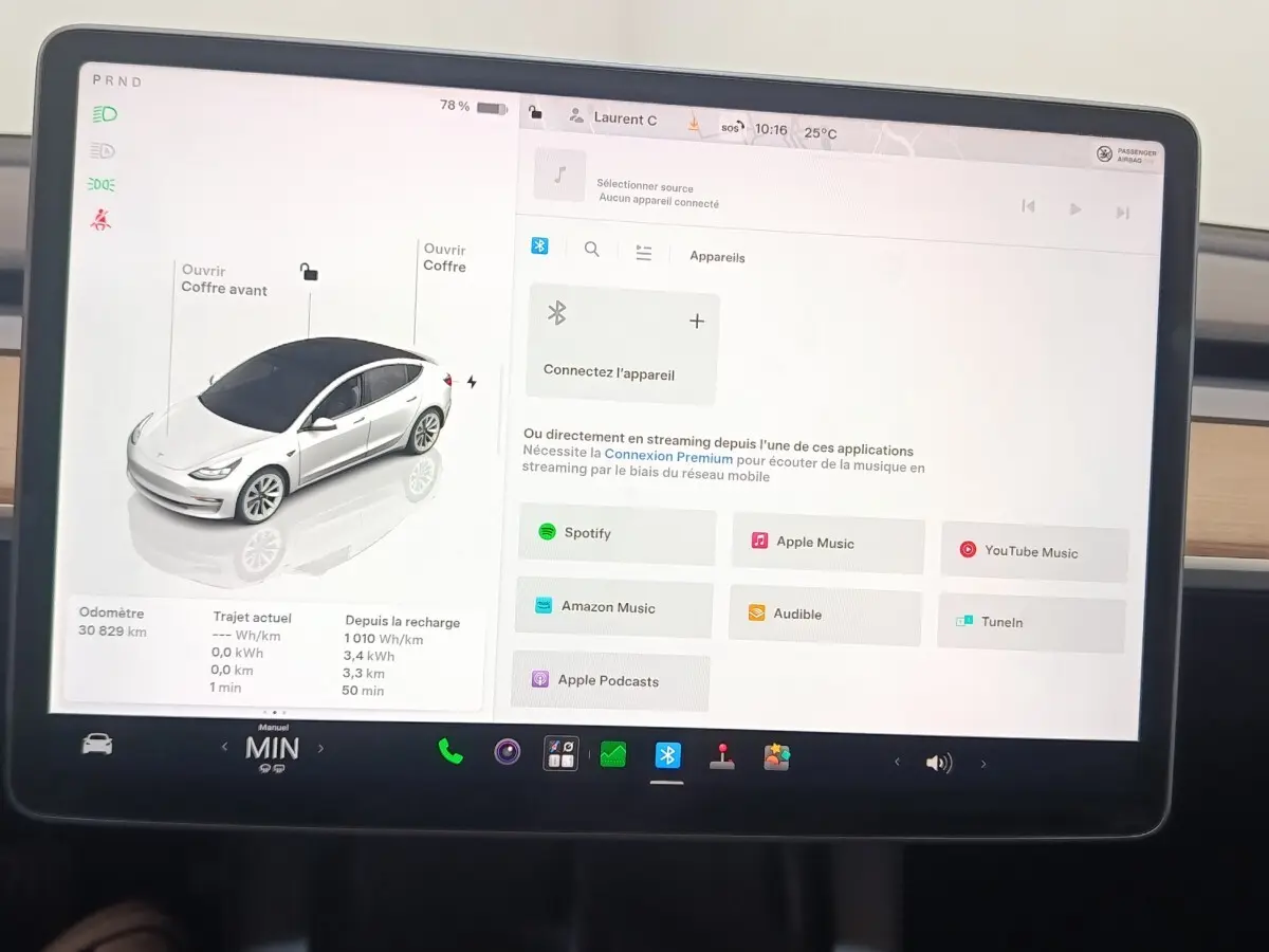 Écran tactile central de Tesla Model 3 blanc 2022 montrant interface multimédia et vue 3/4 avant du véhicule.