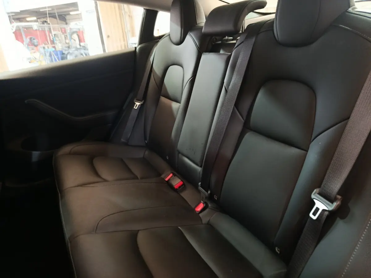 Vue intérieure de la banquette arrière en cuir noir du Tesla Model 3 Grande Autonomie 2022, avec ceintures de sécurité visibles.