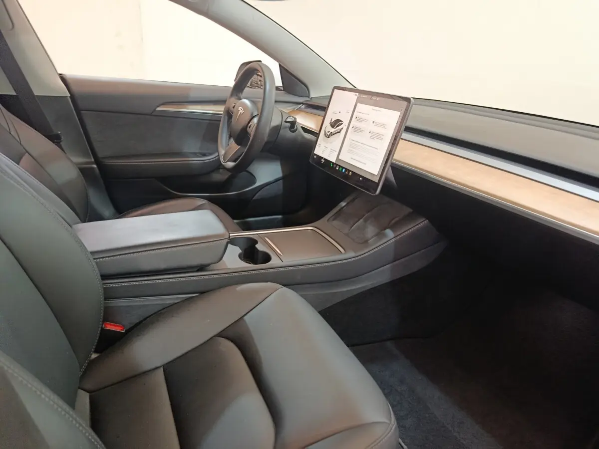 Intérieur Tesla Model 3 Grande Autonomie 2022, vue côté conducteur, sièges noirs et écran tactile central bois clair.