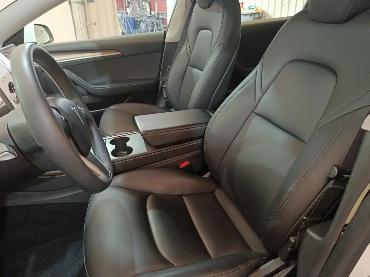 Intérieur de la Tesla Model 3 Grande Autonomie 2022, vue côté conducteur sur sièges en cuir noir et volant multifonction.