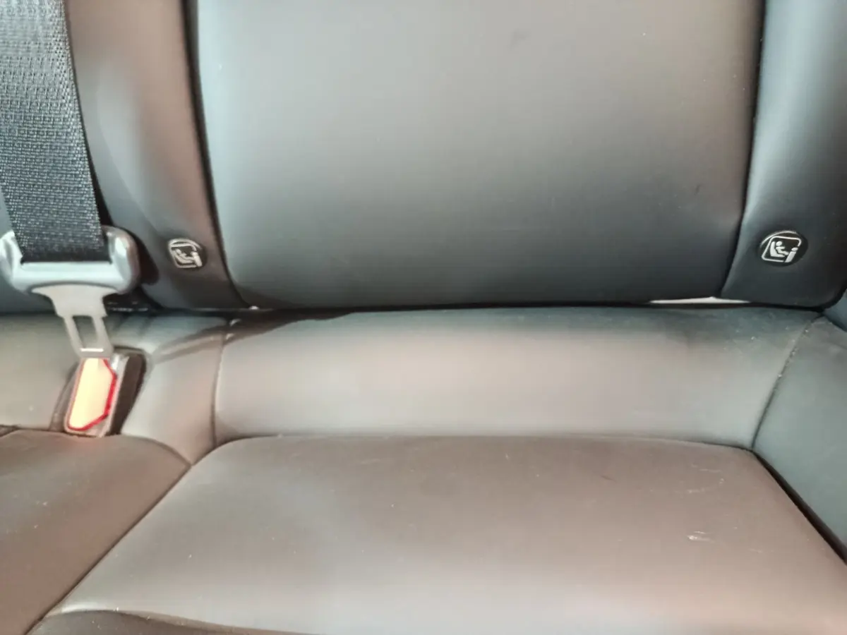 Gros plan sur la banquette arrière noire de la Tesla Model 3 Grande Autonomie 2022, avec ceintures et ancrages Isofix visibles.