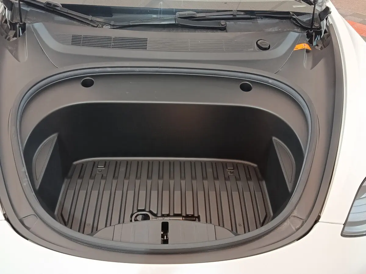 Coffre avant ouvert d'une Tesla Model 3 Grande Autonomie blanche, vue plongeante sur l'espace de rangement vide.