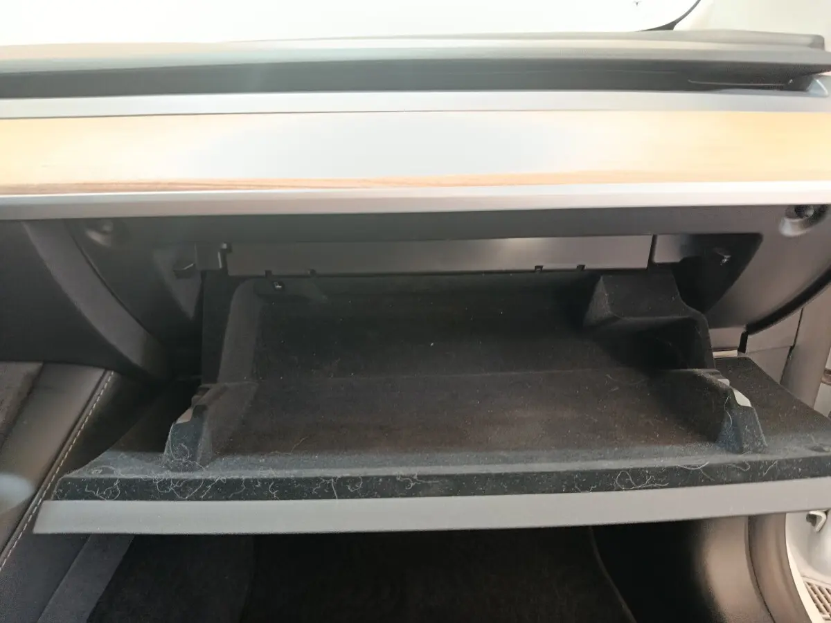Intérieur de la Tesla Model 3 Grande Autonomie 2022, vue sur la boîte à gants ouverte avec finition bois clair au-dessus.