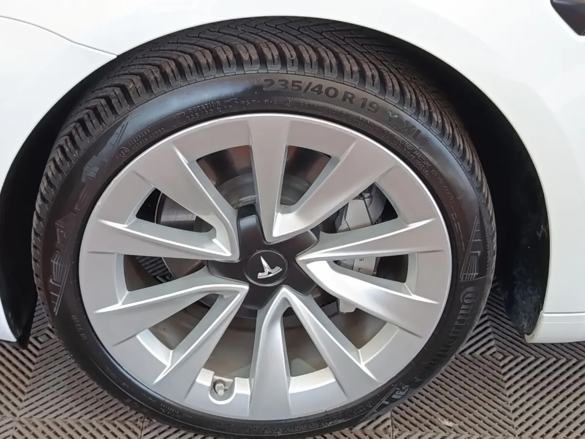 Gros plan sur la roue avant gauche blanche d'une Tesla Model 3 Grande Autonomie 2022 avec jante argentée distinctive.