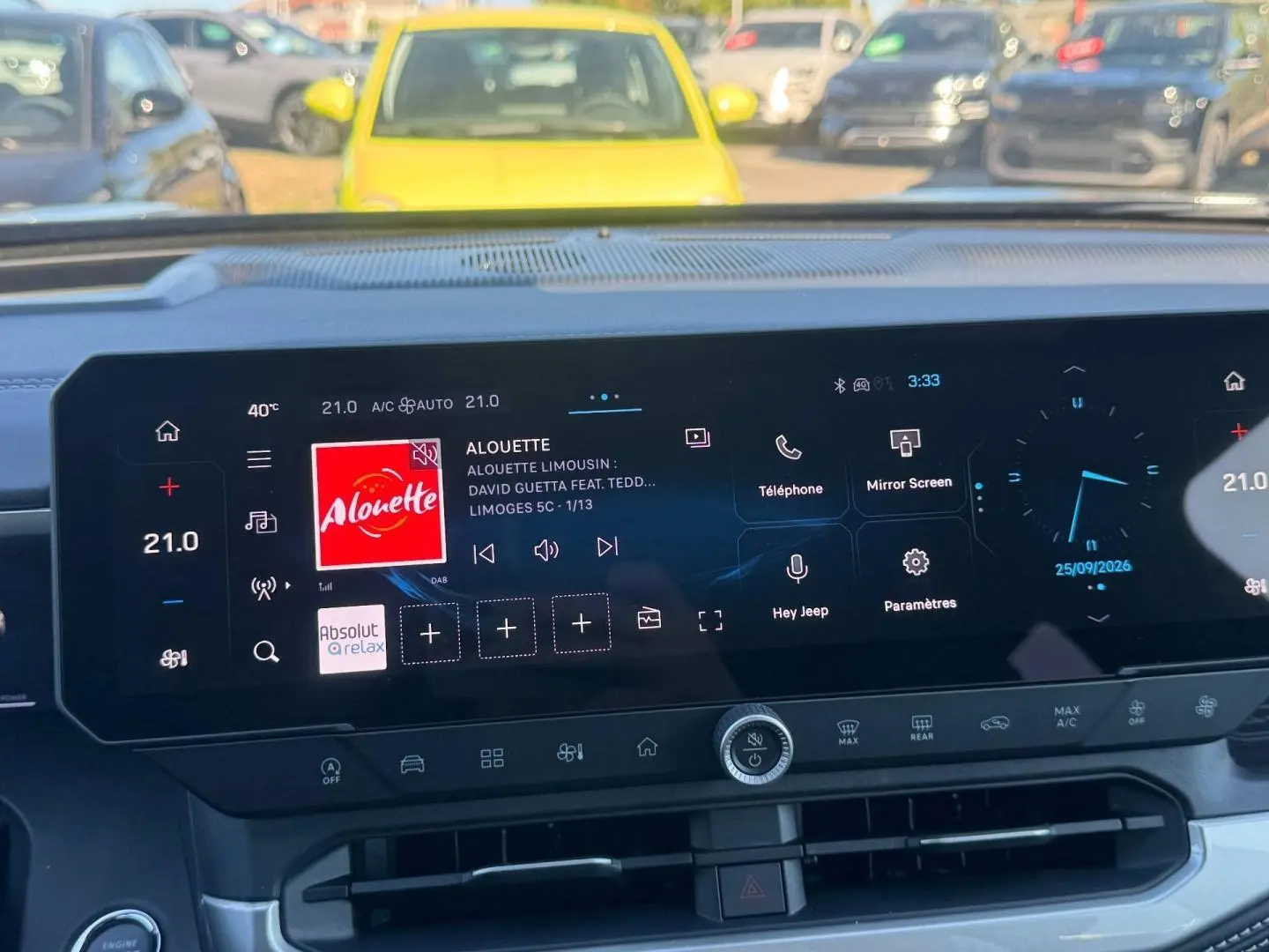 Écran tactile central du Jeep Compass 2026 affichant la radio et les commandes climatisation, intérieur moderne noir.
